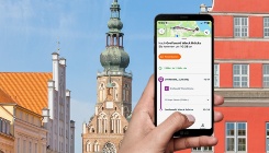 Geöffnete VBG.Deutschland-App auf einem Smartphone vor dem Greifswalder Rathaus im Hintergrund