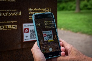 Mithilfe eines Smartphones wird der QR-Code zum Download der Kloster-Eldena-App gescannt