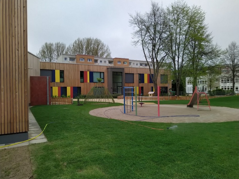 Blick auf den Spielplatz der Kindertagesstätte Tausend Farben in Greifswald mit Rutsche, Klettergerüst und Rasenfläche