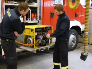 Zwei Feuerwehrmänner prüfen den Stromerzeuger in einem Feuerwehrfahrzeug