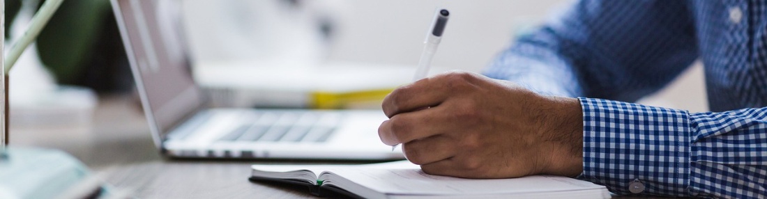 Bild von StockSnap auf Pixabay 1280x333 © StockSnap auf Pixabay Mann schreibt auf Blatt Papier, Laptop im Hintergrund