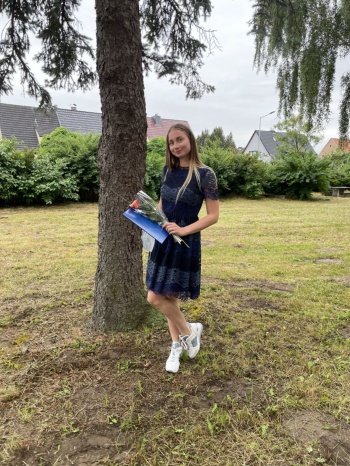 Juliana Irkliievska Juliana Irkliievska steht auf einer Wiese mit ihrem Abschlusszeugnis und einer Rose in der Hand
