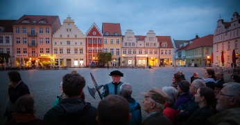Der Greifswalder Nachtwächter führt seine Gäste über den nächtlich beleuchteten Marktplatz
