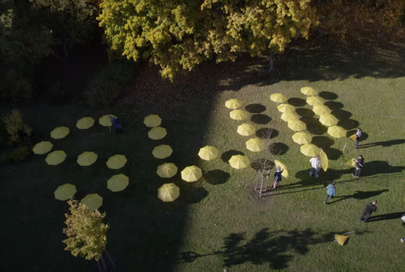 Bewegung der Sonnenschirme in Schönwalde II © Screenshot Youtube Luftbild von gelben Sonnenschirmen die den Schriftzug "SW II" bilden