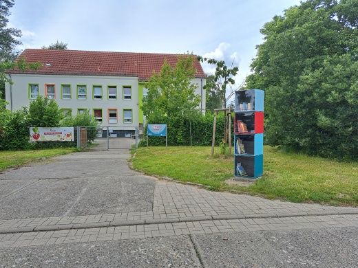 Kinderbücherbaum im Ostseeviertel © Quartierskoordination der Universitäts- und Hansestadt Greifswald Vor einer Kita steht auf einer Wiese ein Bücherbaum in bunten Farben