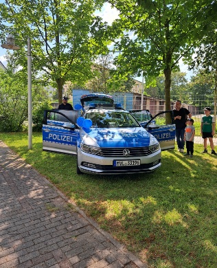 Polizeifahrzeug im Ostseeviertel © Quartierskoordination der Universitäts- und Hansestadt Greifswald Ein Polizeifahrzeug mit geöffneten Türen steht auf einer Wiese mit Bäumen