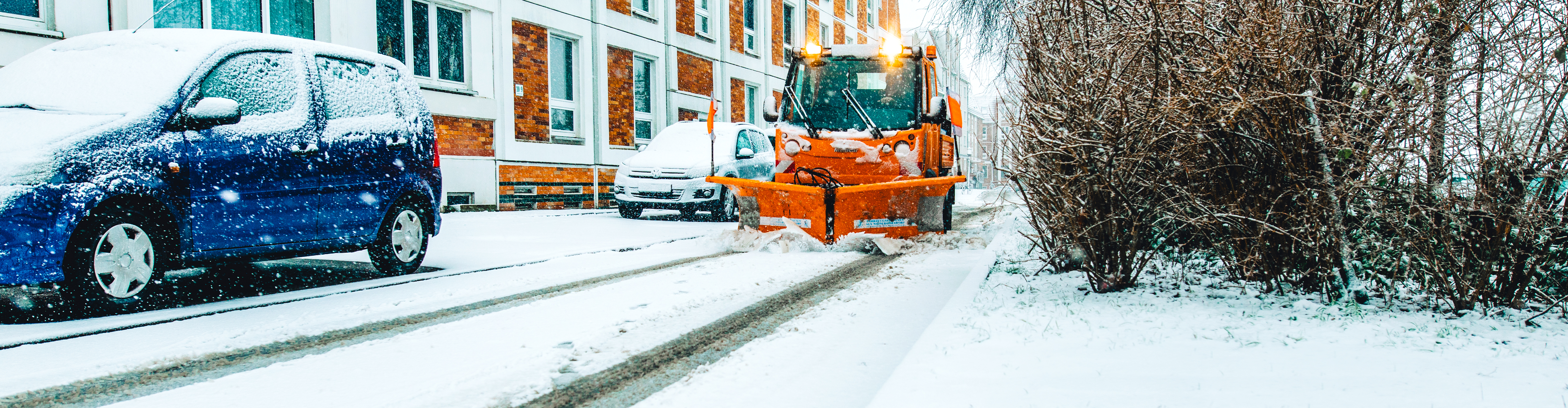 Verschneite Straße, auf der der Winterdienst fährt