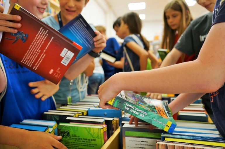 Kinder suchen sich Bücher aus einem Regal aus