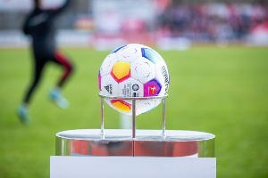 Ein Fußball im Vordergrund mit einem Spieler im Hintergrund