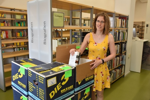 Eine Mitarbeiterin der Stadtbibliothek packt Bücker in Kisten 