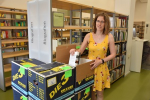 Eine Mitarbeiterin der Stadtbibliothek packt Bücker in Kisten