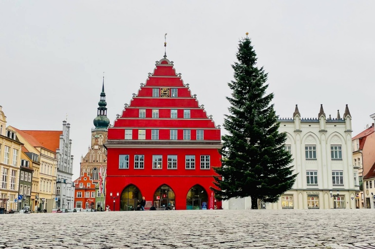 Greifswalder Marktplatz. Vor dem roten Rathaus steht der Weihnachtsbaum.