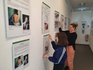 Laura Armborst und Juliette Deforge hängen die Plakate für die Ausstellung Bürgermeister für den Frieden in der STRAZE auf