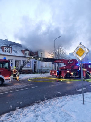 Feuerwehrfahrzeuge vor einem brennenden Gebäude