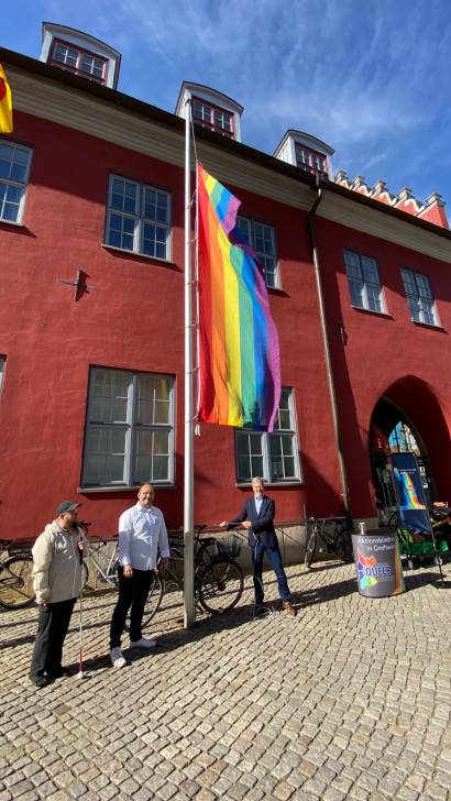 Dr Fassbinder und Mitglieder von Queer hissen die Regenbogenflagge vor dem Rathaus Foto Presesstelle