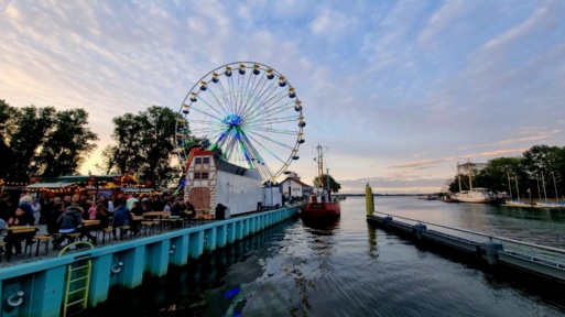 Blick auf den Greifswalder Bodden, das Riesenrad und die Gäste beim Fischerfest gaffelrigg im Jahr 2022.
