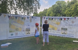 Ein Mädchen und ihre Mutter schauen sich die zwei Spielplatzvarianten auf großen Bannern an - © Stadtverwaltung der Universitäts- und Hansestadt Greifswald Ein Mädchen und ihre Mutter schauen sich die zwei Spielplatzvarianten auf großen Bannern an