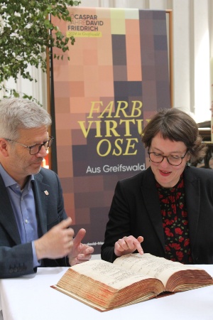 Dr. Stefan Fassbinder und Anett Hauswald sehen sich den Taufeintrag von Caspar David Friedrich an