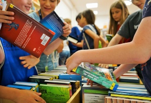 Mehrere Mädchen und Jungen schauen sich Bücher in einer hölzernen Bücherkiste an - © Stadtbibliothek Hans Fallada Mehrere Mädchen und Jungen schauen sich Bücher in einer hölzernen Bücherkiste an