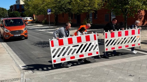 Füf Personen tragen auf einer Straße zwei Verkehrsbaken zur Seite