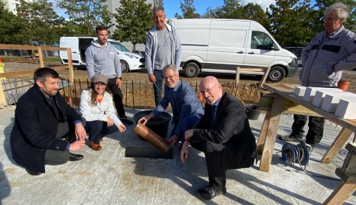 Architekt Denny Blaschka, Baudezernentin Jeannette von Busse, OB Dr. Stefan Fassbinder und Innenminister Christian Pegel lassen eine Zeitkapsel für die Grundsteinlegung der Sporthalle 2 in den Boden ein. 