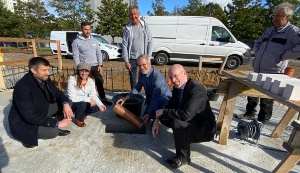 Architekt Denny Blaschka, Baudezernentin Jeannette von Busse, OB Dr. Stefan Fassbinder und Innenminister Christian Pegel lassen eine Zeitkapsel für die Grundsteinlegung der Sporthalle 2 in den Boden ein.