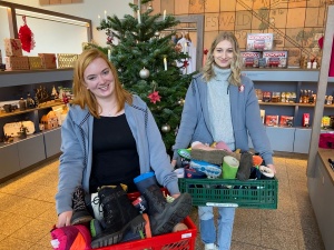 Jenny Lilienthal und Maja-Sophie Krause tragen in der Greifswald-Information Kisten mit Stiefeln