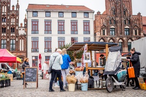 Ein Stand auf dem Regional- und Wochenmarkt, an dem verschiedene Marktbesucher Waren kaufen