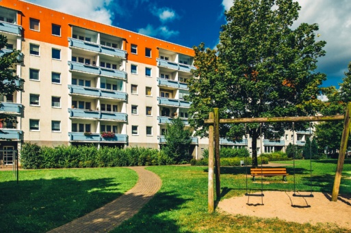 Eine Schaukel und ein Baum stehen vor einem Wohnblock mit Balkonen in Schönwalde II