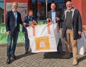 Einer für alle Gelben ©Theres Behnke, GMG (quer) © Theres Behnke, GMG Dr. Stefan Fassbinder (Oberbürgermeister), Dr. Dagmar Riske (Verein zur Unterstützung Krebskranker Kinder e.V. ), Uwe Hoth (REMONDIS Vorpommern), Maik Wittenbecher (Greifswald Marketing GmbH) präsentieren vor der Greifswald-Informationen den großen Sack