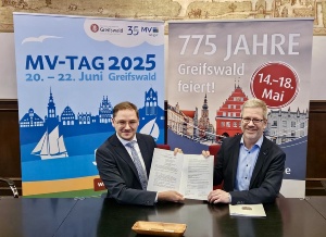 Greifswalds Oberbürgermeister Dr. Stefan Fassbinder (re.) und der Chef der Staatskanzlei MV Patrick Dahlemann mit dem unterzeichneten Vertrag zum MV-Tag 2025