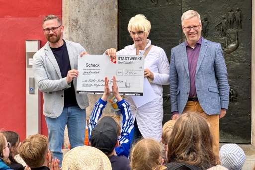 Stefan Lorke von den Stadtwerken und Dr. Stefan Fassbinder gratulieren der Schulleiterin der Kollwitz-Grundschule, Ute Prochnow, zum Sieg.