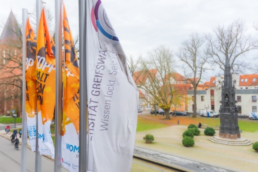 Flaggen zum Orange Day vor dem Hauptgebäude der Universität mit Blick auf das Rubenowdenkmal