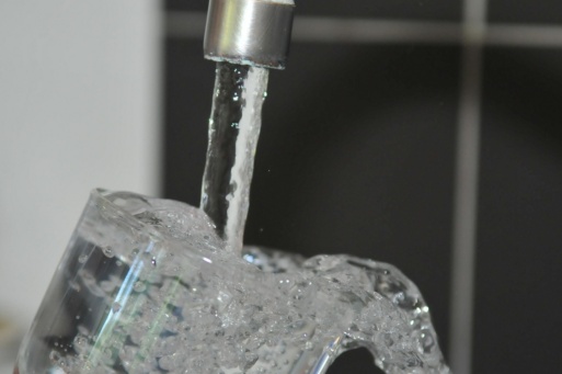 Glas Wasser unter einem laufenden Wasserhahn
