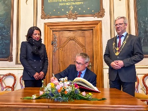 Dänemarks Botschafter Thomas Østrup Møller trägt sich ins Goldene Buch der Stadt ein, links Prof. Madeleine Tolani, rechts Oberbürgermeister Dr. Stefan Fassbinder