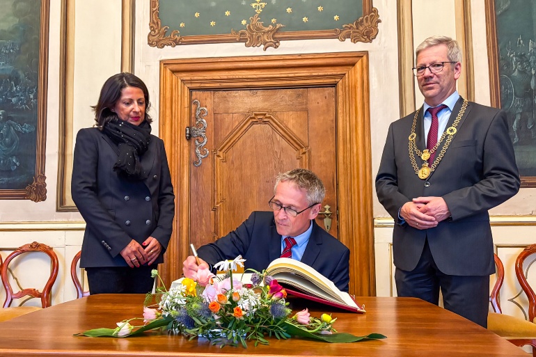 Dänemarks Botschafter Thomas Østrup Møller trägt sich ins Goldene Buch der Stadt ein, links Prof. Madeleine Tolani, rechts Oberbürgermeister Dr. Stefan Fassbinder