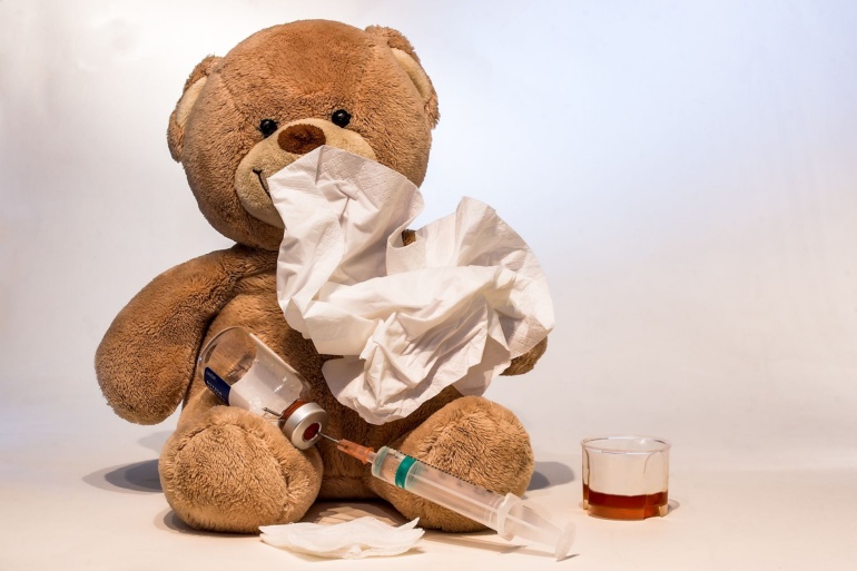 Kranker Plüschteddy mit Spritze und Taschentüchern