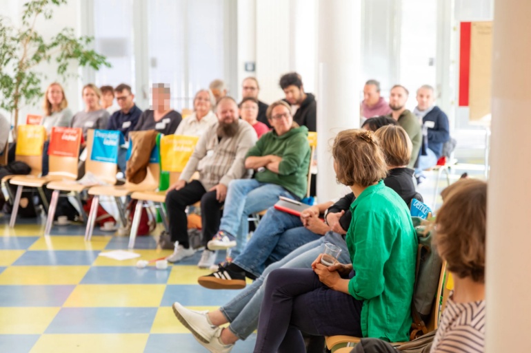 Menschen sitzen in einem Plenum und sind in eine gemeinsame Diskussion vertieft