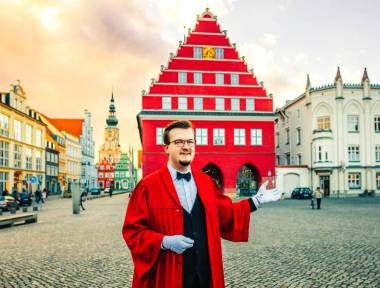 Im Talar gewandeter Stadtführer vor dem Rathaus