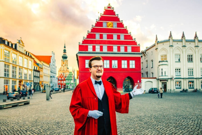 Im Talar gewandeter Stadtführer vor dem Rathaus Im Talar gewandeter Stadtführer vor dem Rathaus